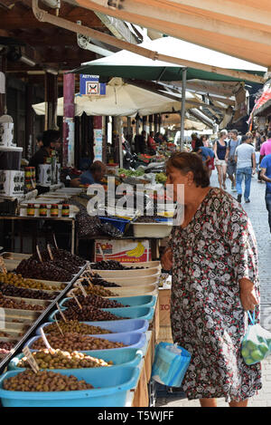 ATHENS, GREECE - AUGUST 29, 2018: Woman looking at stand with fresh olives for sale at farmers market. Stock Photo