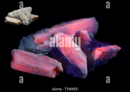 Crystals of major industrial lithium ore spodumene showing red fluorescence in ultraviolet light (365 nm).  Smaller image same sample in normal light. Stock Photo