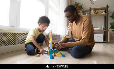 Father and son sitting on floor play with toy blocks Stock Photo