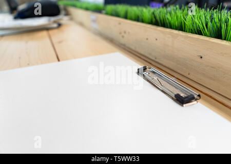 white empty plastic clipboard lay on the wood table. Stock Photo