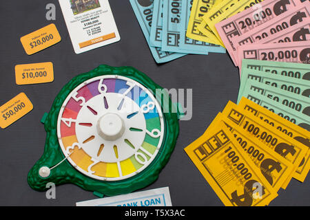 'RAK, RAK, UAE - 4/20/2019 : Top view of colourful Game of Life  Money fanned out on the table and set-up materials. Family fun for all ages strategiz