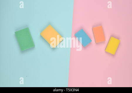 Many multi-colored sponges for cleaning on a pink blue pastel background. Trend of minimalism. Top view. Stock Photo