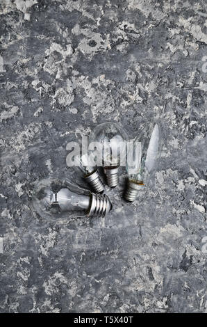 Many different types of incandescent bulbs on a gray concrete background. The interior is loft style. Stock Photo