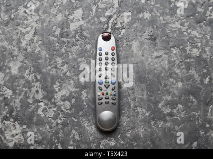 The TV controls on a gray concrete table. Top view. Remote control of home appliances and electronics. Stock Photo
