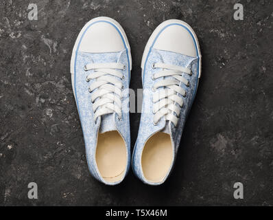 Stylish retro sneakers from 80s on a black concrete floor. Top view. Stock Photo