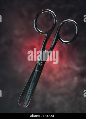 Metal scissors on the background of a concrete wall. Mystical red light. Stock Photo
