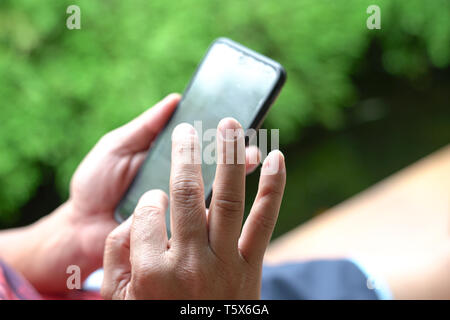 Closeup or cropped view of man's hands surfing or reading his mobile phone Stock Photo