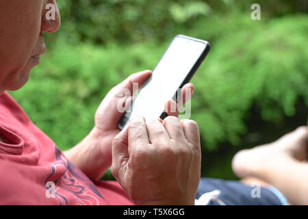 Closeup or cropped view of man's hands surfing or reading his mobile phone Stock Photo