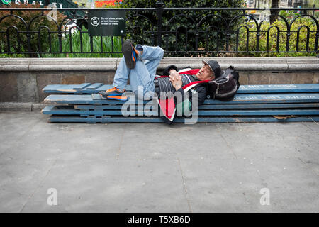 A man having a nap on some wooden planks outsdoors in Union Square Park in lower Manhattan, New York City. Stock Photo