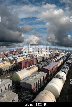 Railroad cars on a railway station. Cargo transportation. Storm clouds above train. Panoramic view. Wide angle Stock Photo