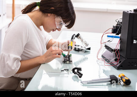 Female Engineer Or Tech Repairs Electronic Device In Hardware Repair Shop Stock Photo