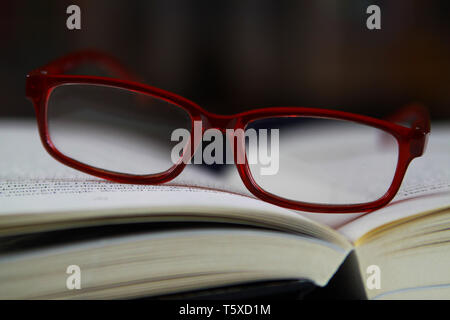View on pages of open book with red reading glasses Stock Photo