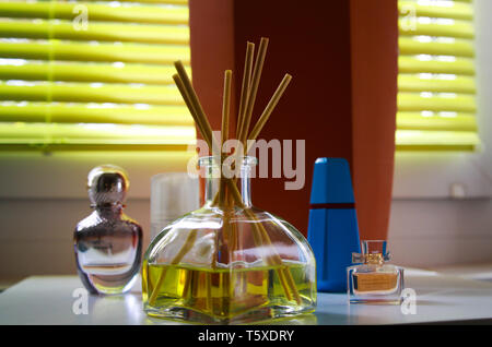 Fragrance diffusor glass with reed sticks between perfume flacons giving natural scent of lemon Stock Photo