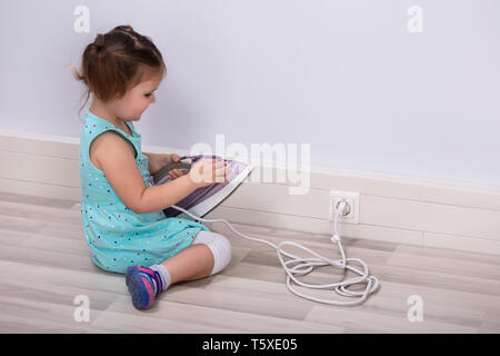 Toddler Trying To Insert Iron Wire In Electric Plug At Home Stock Photo