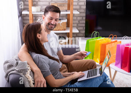 Side View Of Happy Couple Using Credit Card While Shopping Online On Laptop Stock Photo