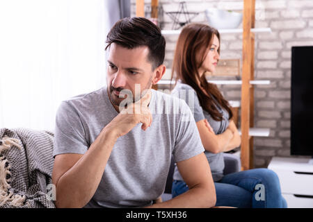 Young Depressed Couple Sitting On Sofa At Home Stock Photo