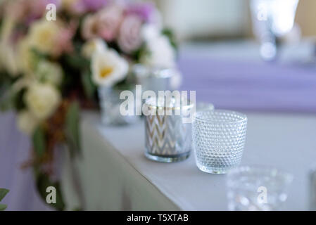 Small candlesticks on a table of a groom and a bride. Stylish, fashionable details of a decor of a modern wedding Stock Photo
