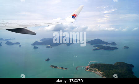 KEDAH, LANGKAWI, MALAYSIA - APR 11th, 2015: Scenery from airplane window seeing wing of airplane, white clouds, blue sky and beautiful islands Stock Photo