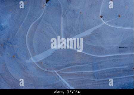 Detail of a frozen puddle captured on a frosty winter morning reveals abstract shapes and patterns of icy structures in white and blue Stock Photo