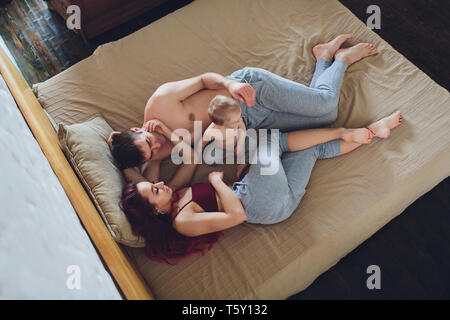 happy young parents with baby in the bed at home.