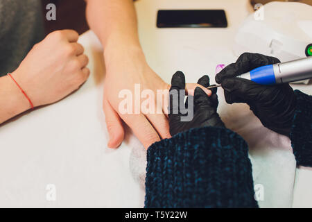 Hands in gloves cares about man's hand nails. Manicure beauty salon.