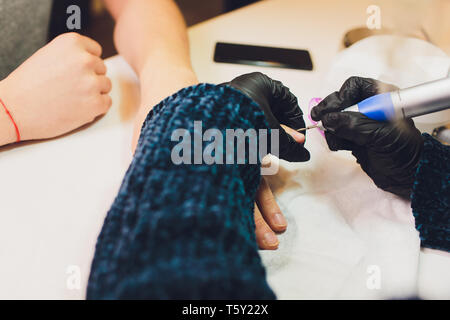Hands in gloves cares about man's hand nails. Manicure beauty salon.