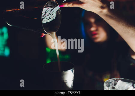 female bartender. girl with blue hair. cocktail making in night bar. Stock Photo