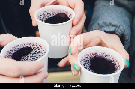 two hands and three full plastic cups with mulled wine. Stock Photo