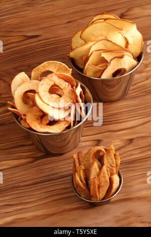 Apple and pear chips in metal bowls on a wooden table. Closeup. Macro Stock Photo