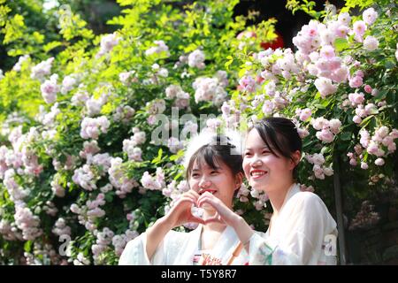 Nanjing, China's Jiangsu Province. 27th Apr, 2019. Two women pose for a photo with blooming flowers at a scenic spot in Nanjing, east China's Jiangsu Province, April 27, 2019. Credit: Liu Jianhua/Xinhua/Alamy Live News Stock Photo