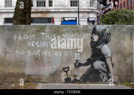 London, UK.  27 April 2019.  An artwork has appeared on a wall at Marble Arch following ten days of protests in London by Extinction Rebellion, a group demanding that governments take action to tackle climate change.  Now covered in a protective plastic cover, the artwork has been attributed to the celebrated street artist Banksy and depicts an image of a plant and a girl holding a gardening tool with the Extinction Rebellion logo on it next to the text 'From this moment despair ends and tactics begin'.  Credit: Stephen Chung / Alamy Live News Stock Photo