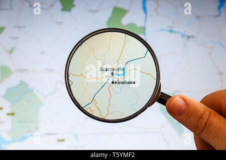 Kinshasa, Congo Democratic Republic. Political map. City visualization illustrative concept on display screen through magnifying glass in the hand. Stock Photo