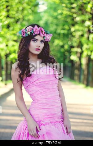 Brunette woman in flowers crown and pink dress outdoor Stock Photo