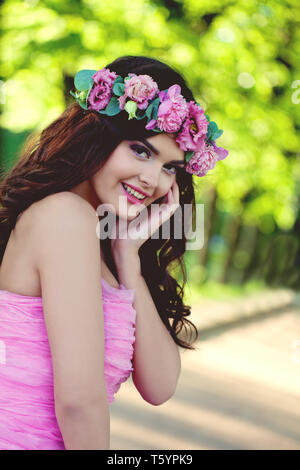 Cheerful brunette woman outdoors portrait. Smiling model with flowers Stock Photo