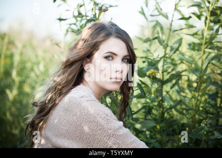 Pretty woman outdoors. Beautiful female model in organic cotton sweater on green grass background Stock Photo