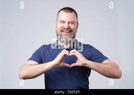 Mature european man with beard making out of the hands heart. Stock Photo