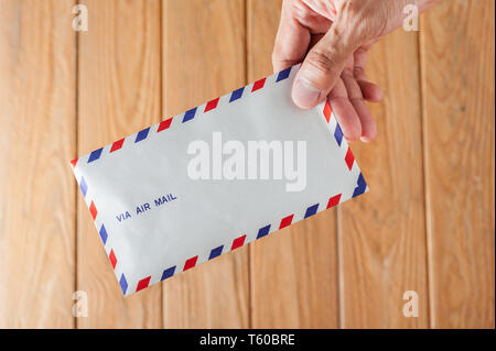 air mail envelope in hand over wood background Stock Photo
