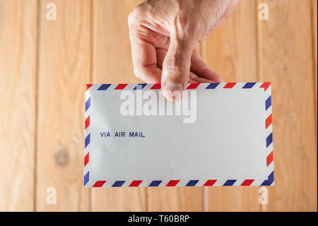 air mail envelope in hand over wood background Stock Photo