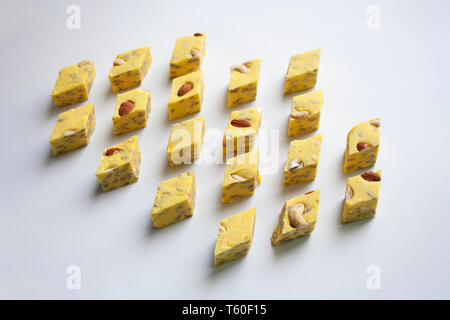 Yellow halva slices with melon taste stuffed with almond and cashew nuts isolated on white background Stock Photo
