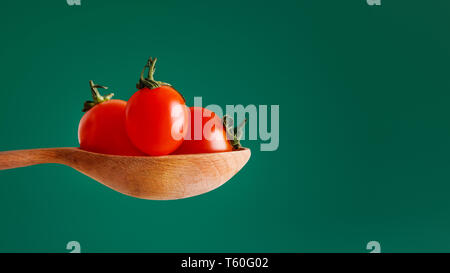 Cherry tomatoes in spoon on green Stock Photo