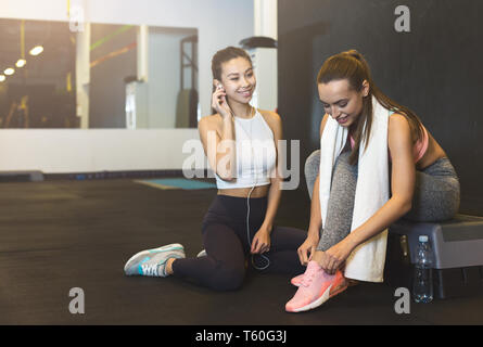 Preparing for workout. Athlete women lacing shoes and talking Stock Photo