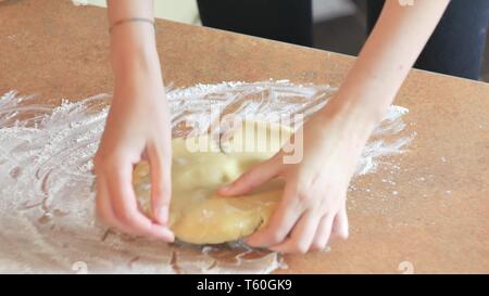 Female hands kneading dough in flour on table Stock Photo