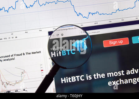 MONTREAL, CANADA - APRIL 26, 2019: HitBTC cryptocurrency digital assets exchange logo and home page on a laptop screen under magnifying glass. Stock Photo