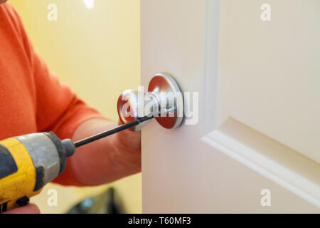 Handyman repair worker's hands installing new door locker man repairing the doorknob. closeup Stock Photo