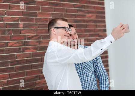 two young men taking selfies standing near a brick wall .people and technology Stock Photo