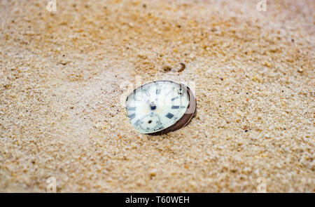 Sands of time. Antique rotten pocket watch buried partial in the sand. Stock Photo