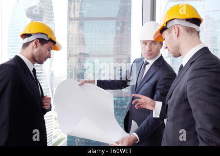 Businessmen and architect team in office planning construction project with office buildings Stock Photo