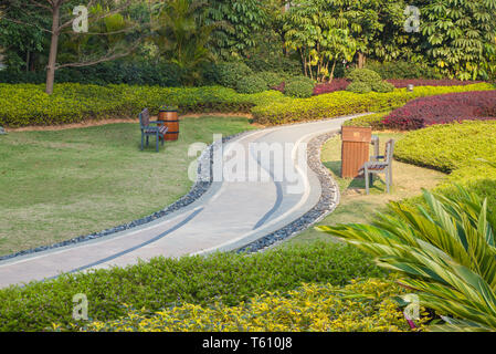 Beautiful summer garden with a walkway winding its way through. The curve walkway with stone tile on green grass field and flowerbed with table and fl Stock Photo
