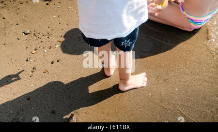 Closeup image of childs feet on sea beach