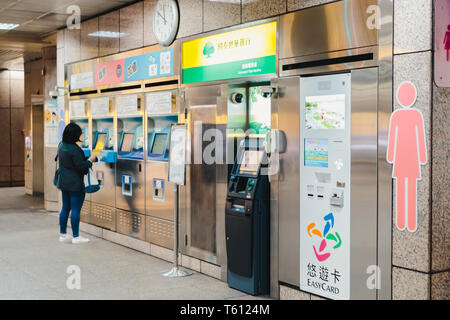 Asian woman buying a metro train ticket from an automatic ticket machine in at a metro station in Taipei